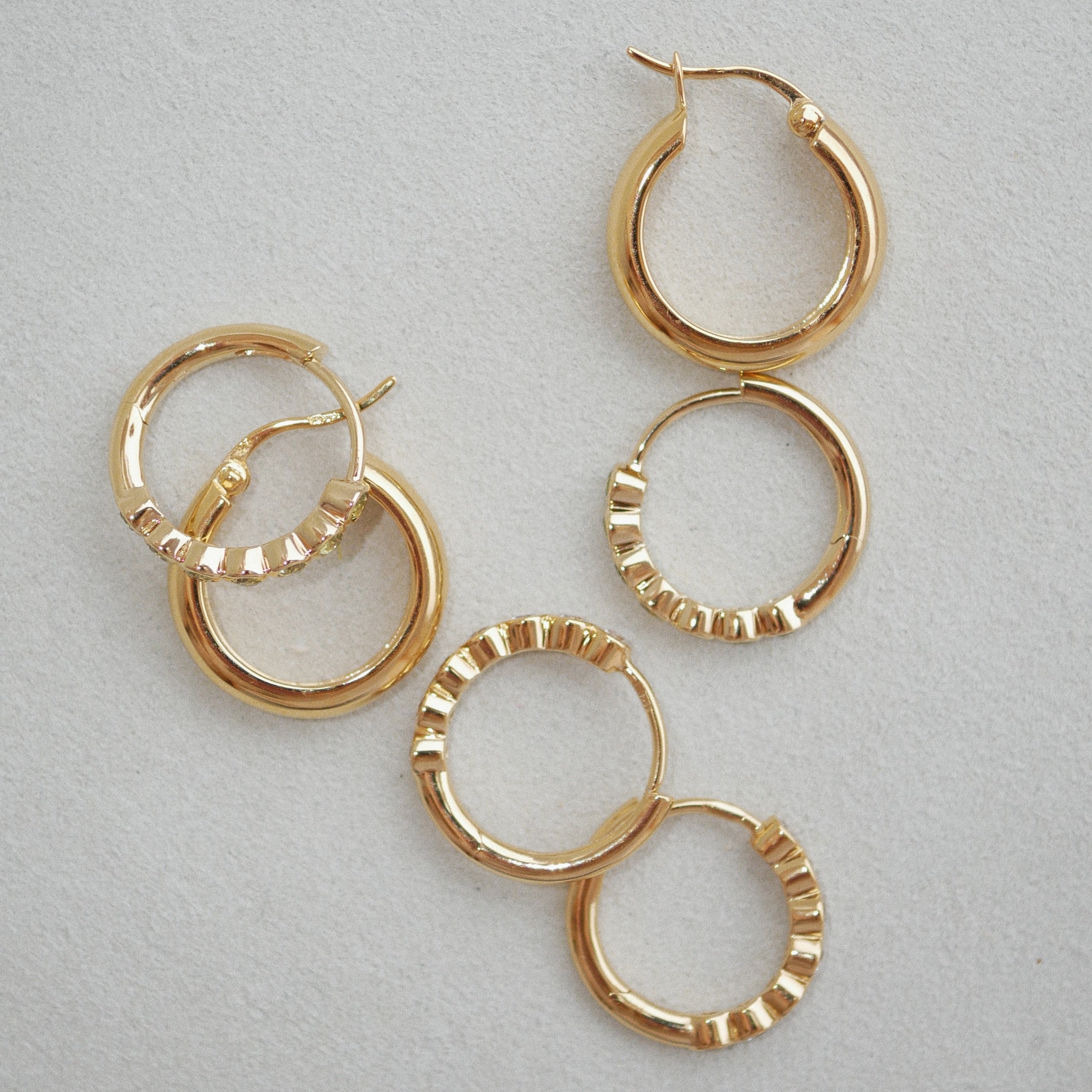 Gold hoop earrings on a light gray background