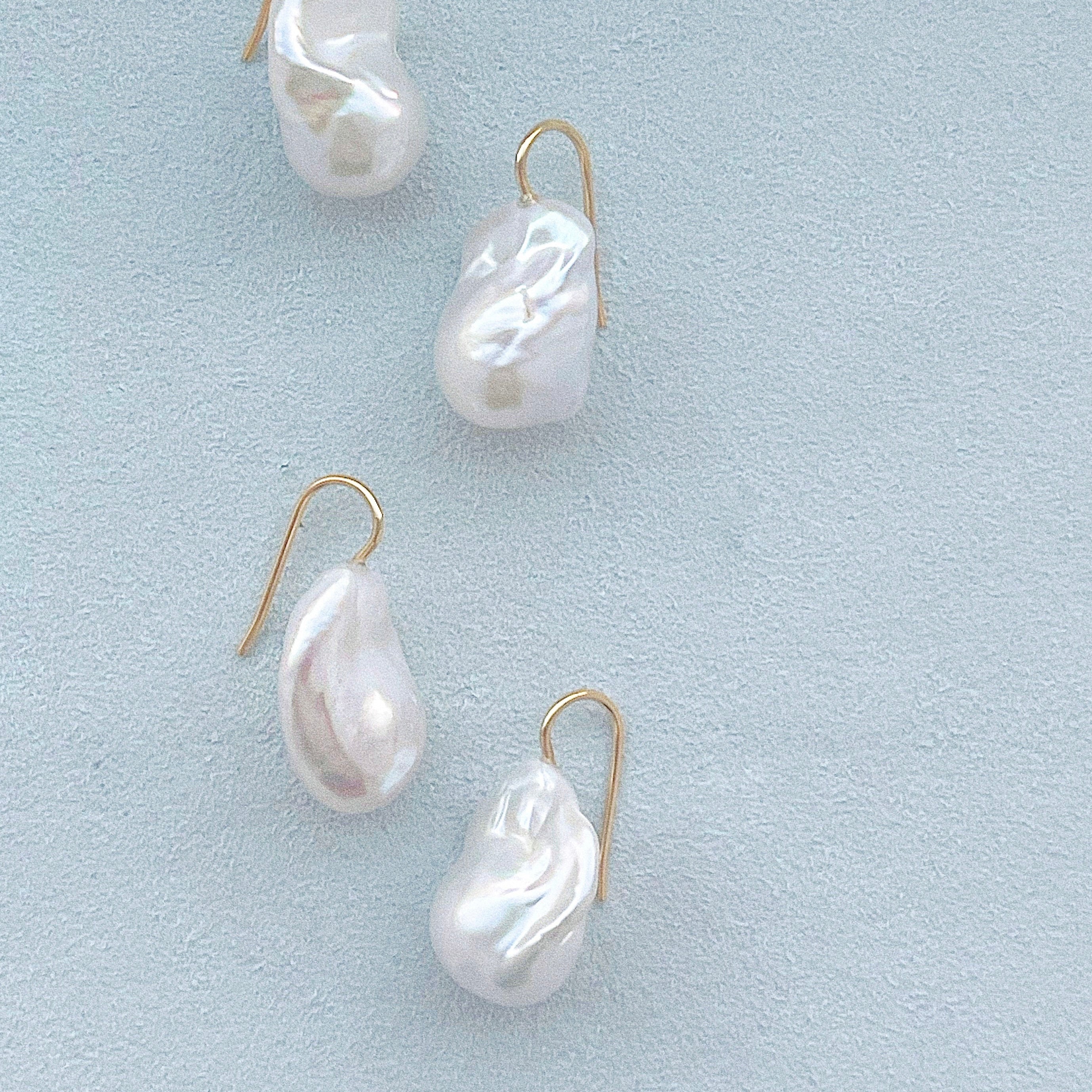 Set of four pearl earrings on a light blue background