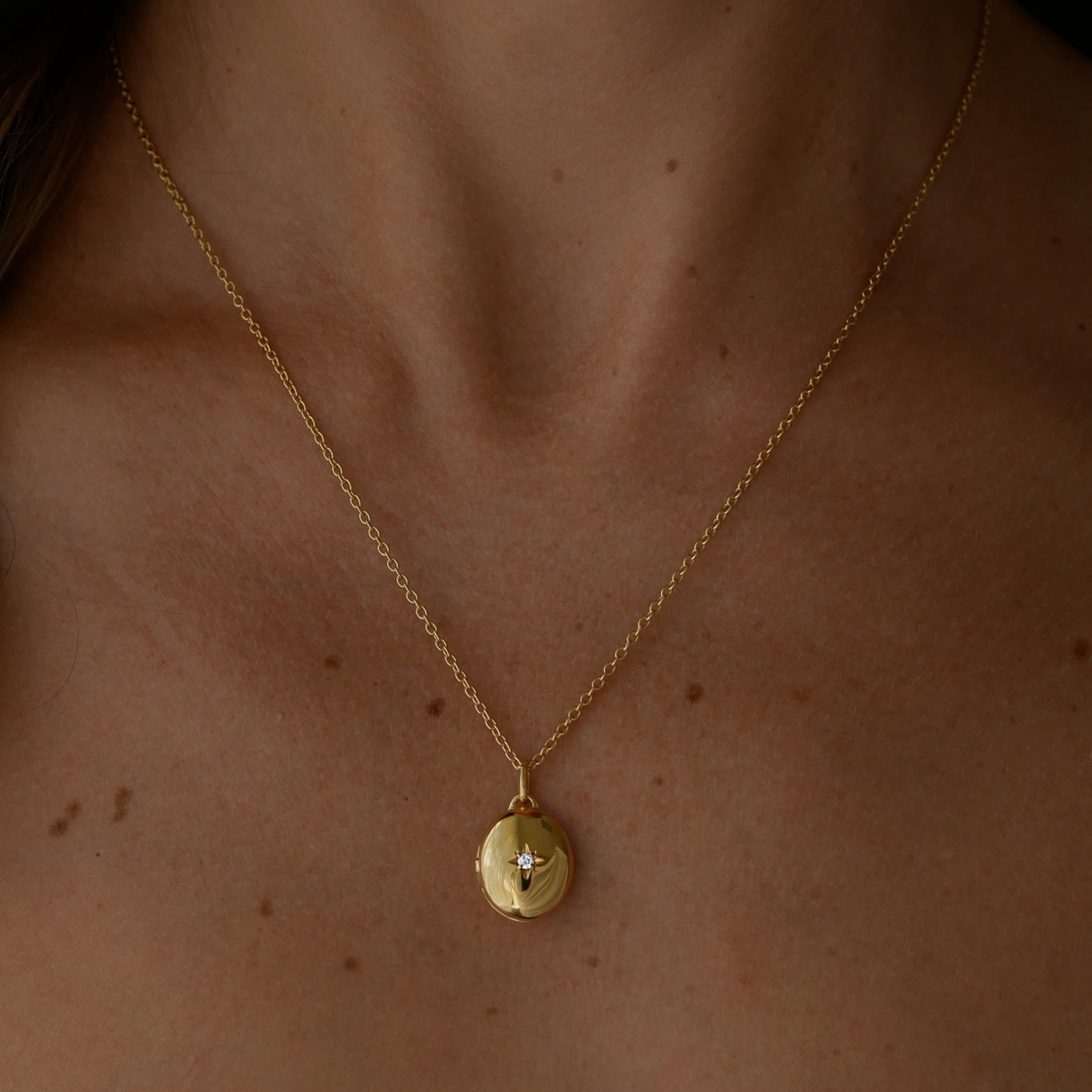 Gold vermeil necklace with a pendant , an oval locket on a person's neck 