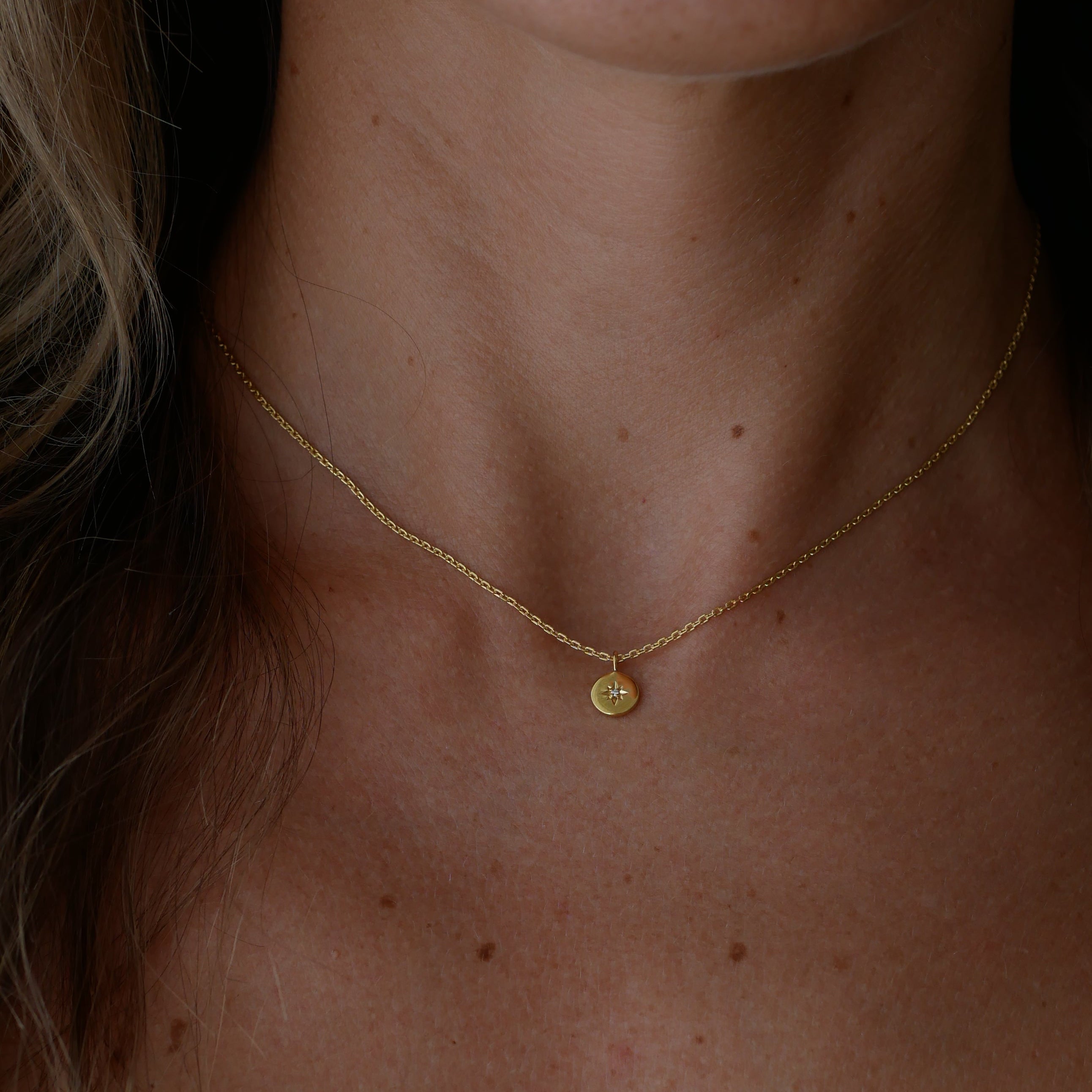 Close-up of a gold necklace on a womans neck with a dark background