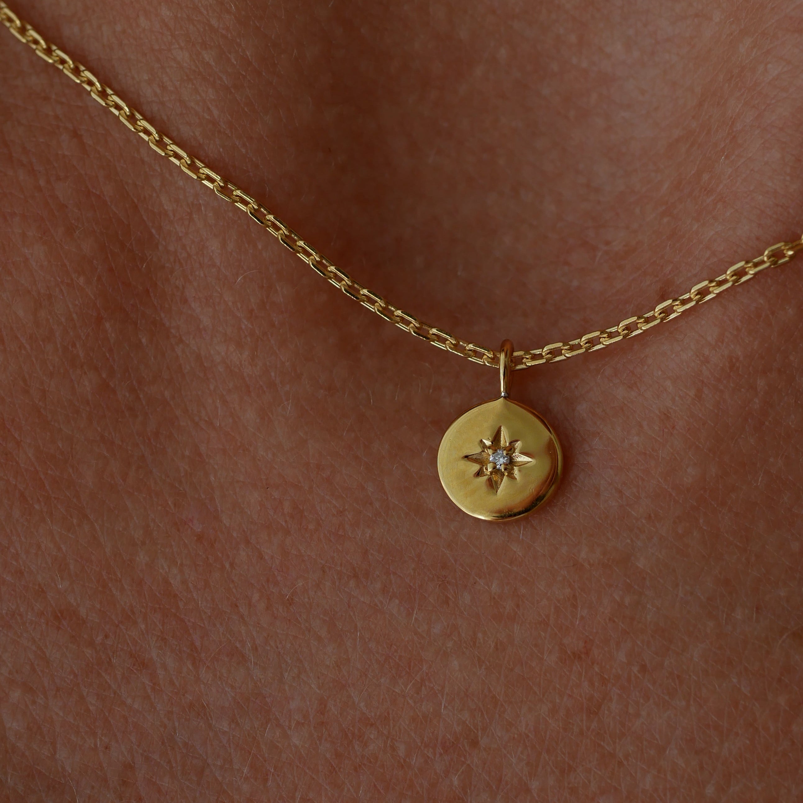 Gold necklace with a small round pendant on skin
