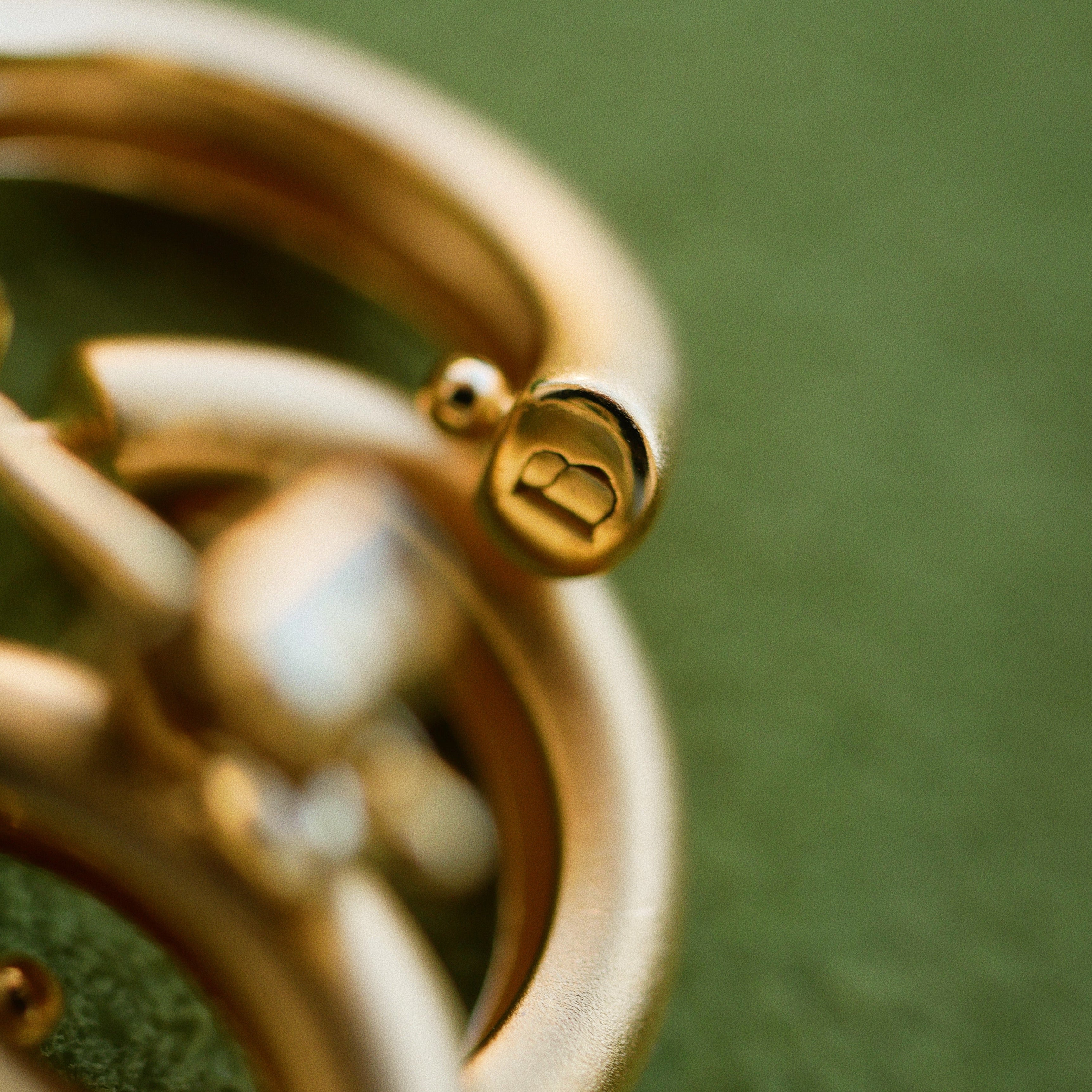 Gold bracelet with a brand logo on a green background