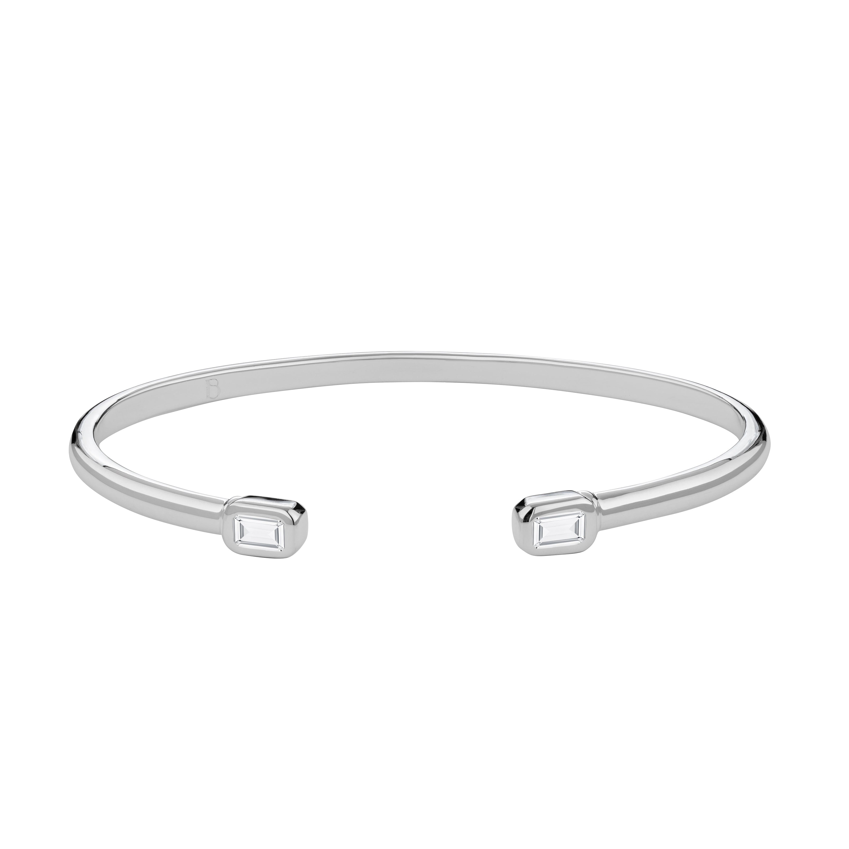 A silver cuff bracelet featuring two baguette-cut clear topaz stones set in the center.