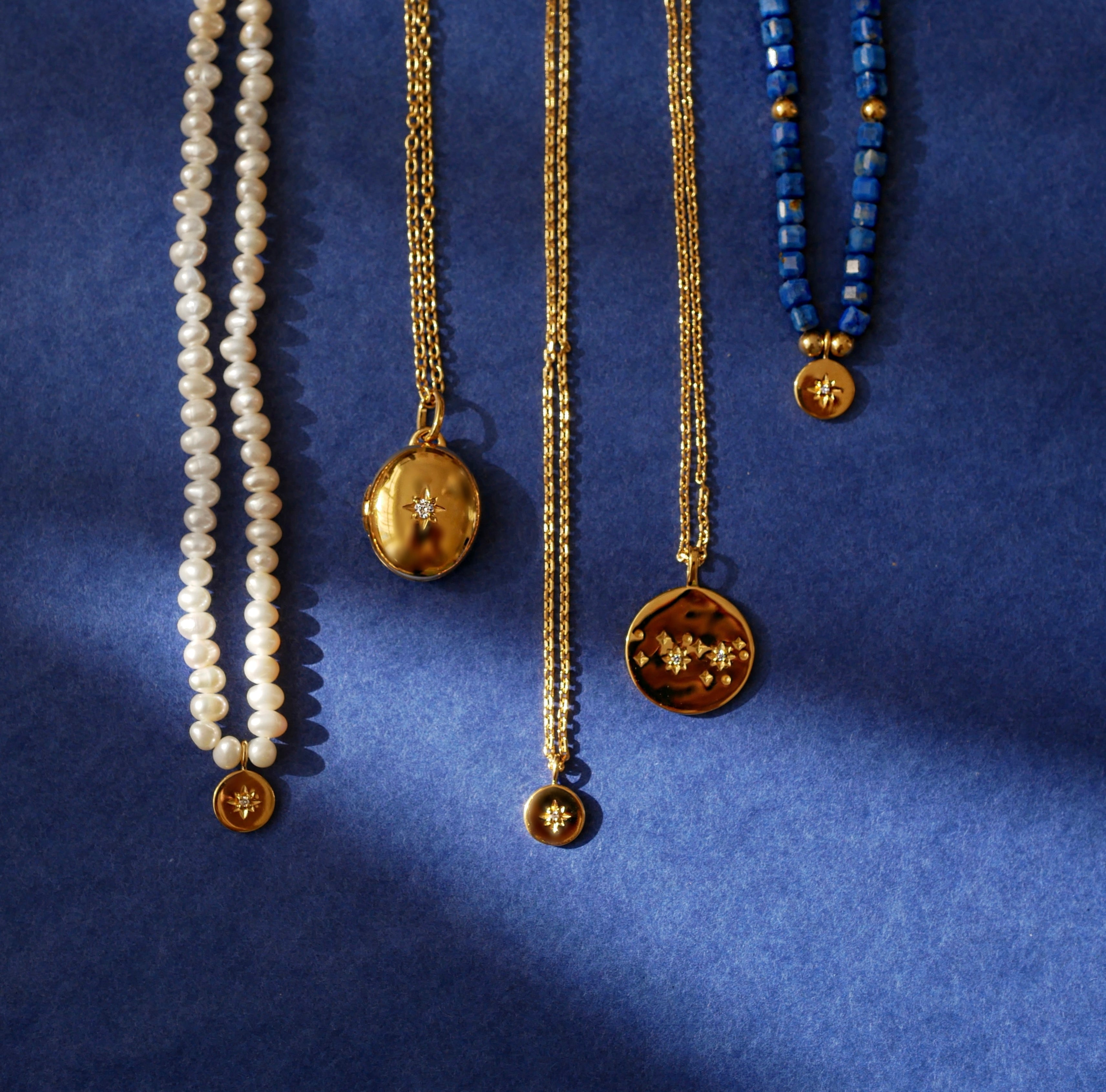 Four necklaces with different pendants on a blue background